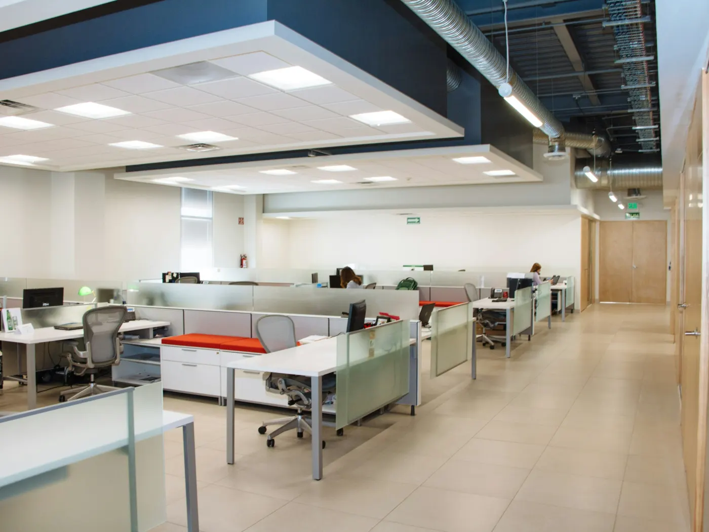 Rows of white desks and frosted glass partitions in a small studio